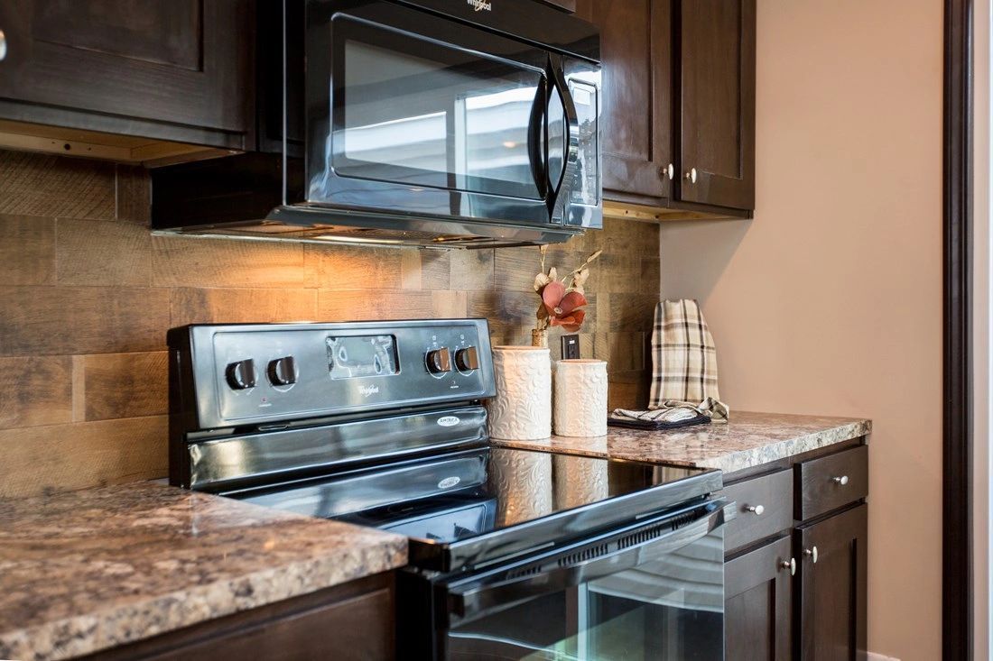 A kitchen with a stove , microwave , and refrigerator.