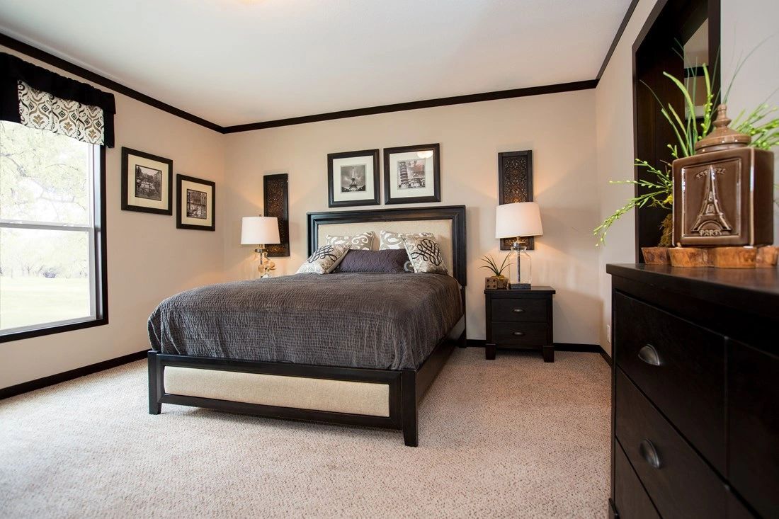 A bedroom with a bed , nightstand , dresser and window.