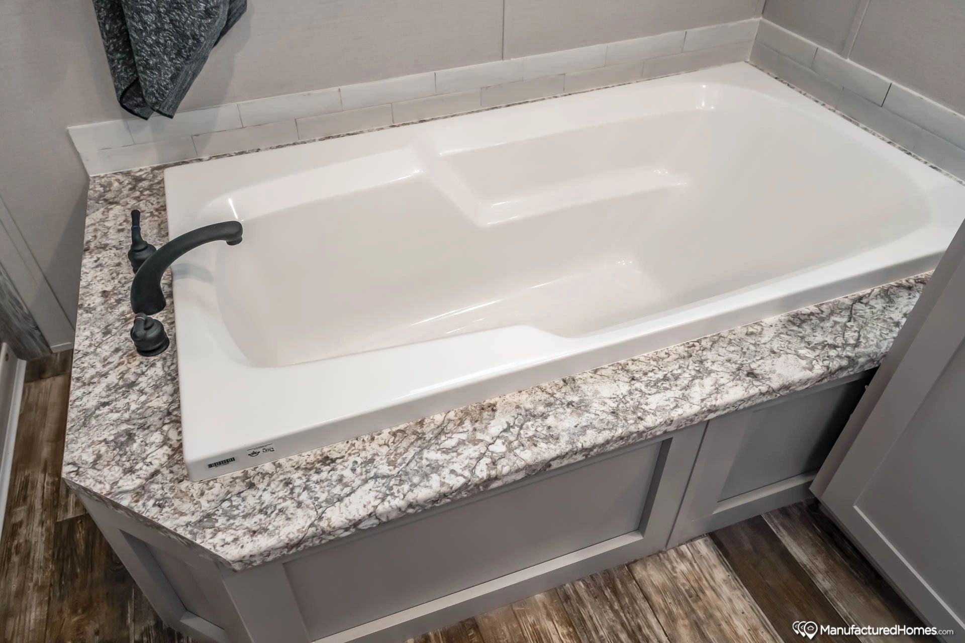 A bathtub is sitting on top of a granite counter in a bathroom.