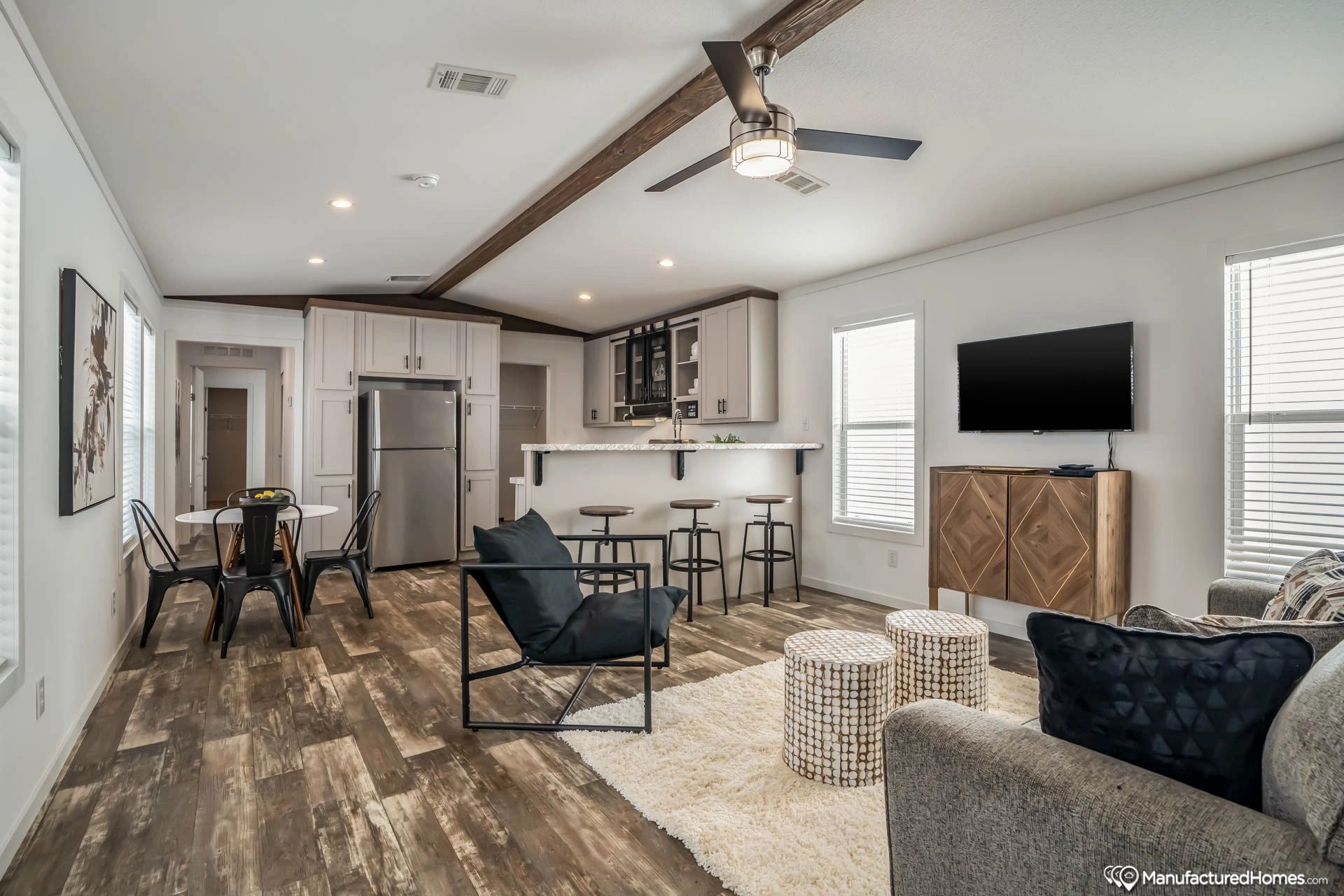 A living room with a couch , chair , television and a ceiling fan.