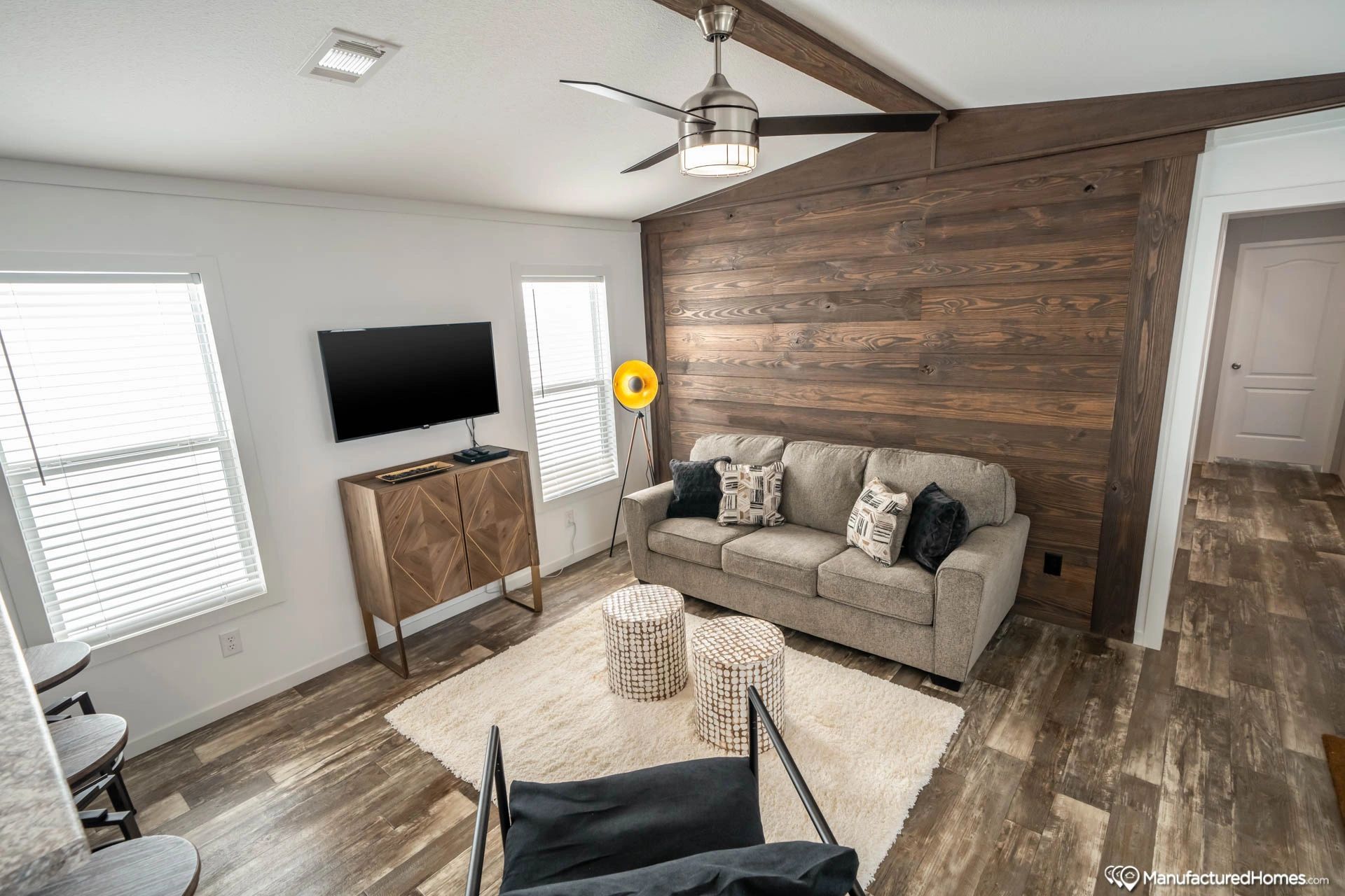 A living room with a couch , television , and ceiling fan.