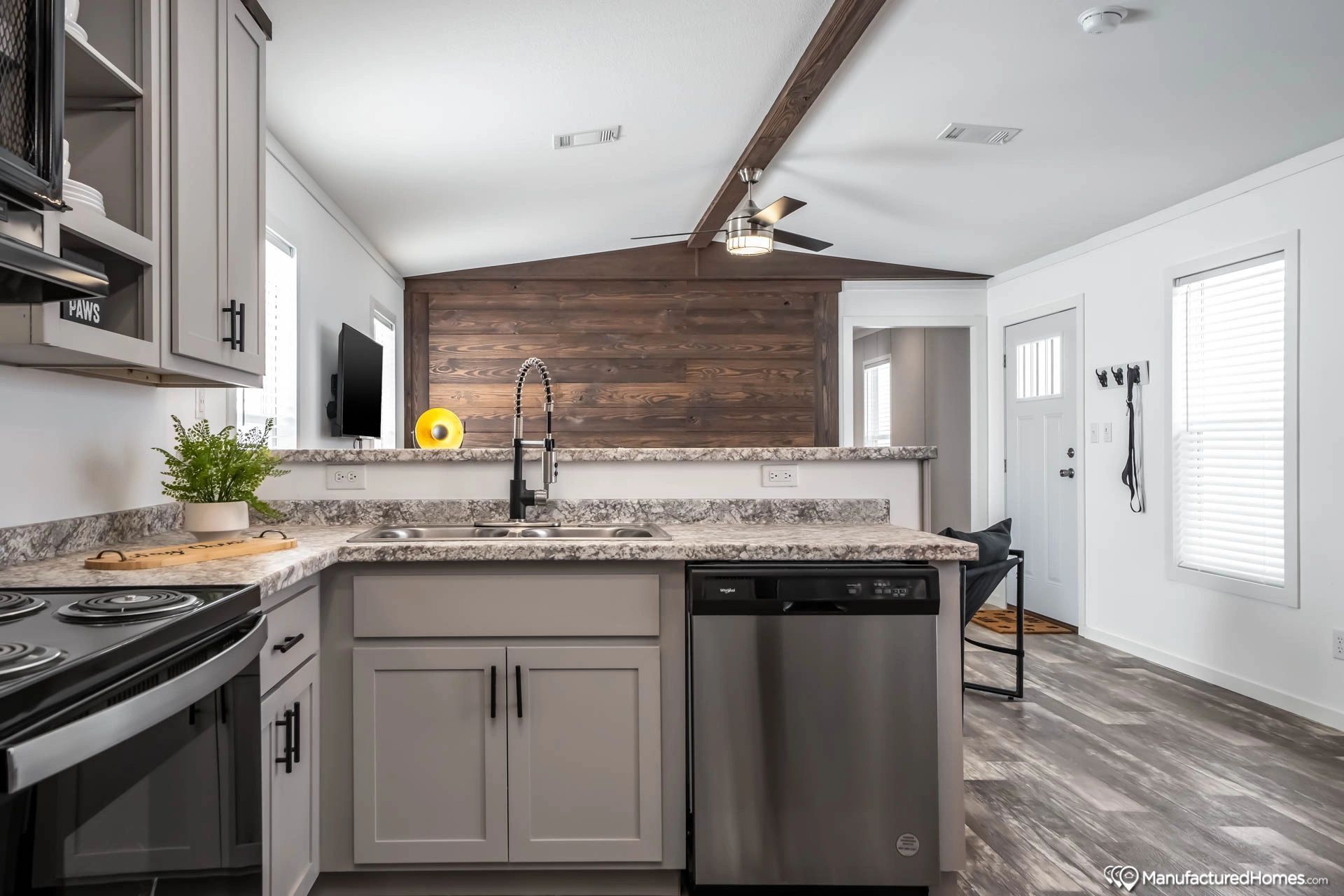 A kitchen in a mobile home with stainless steel appliances and granite counter tops.