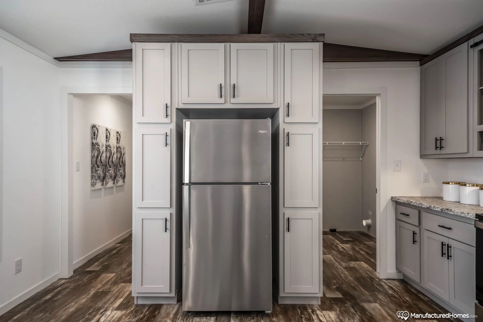 A kitchen with white cabinets and a stainless steel refrigerator.