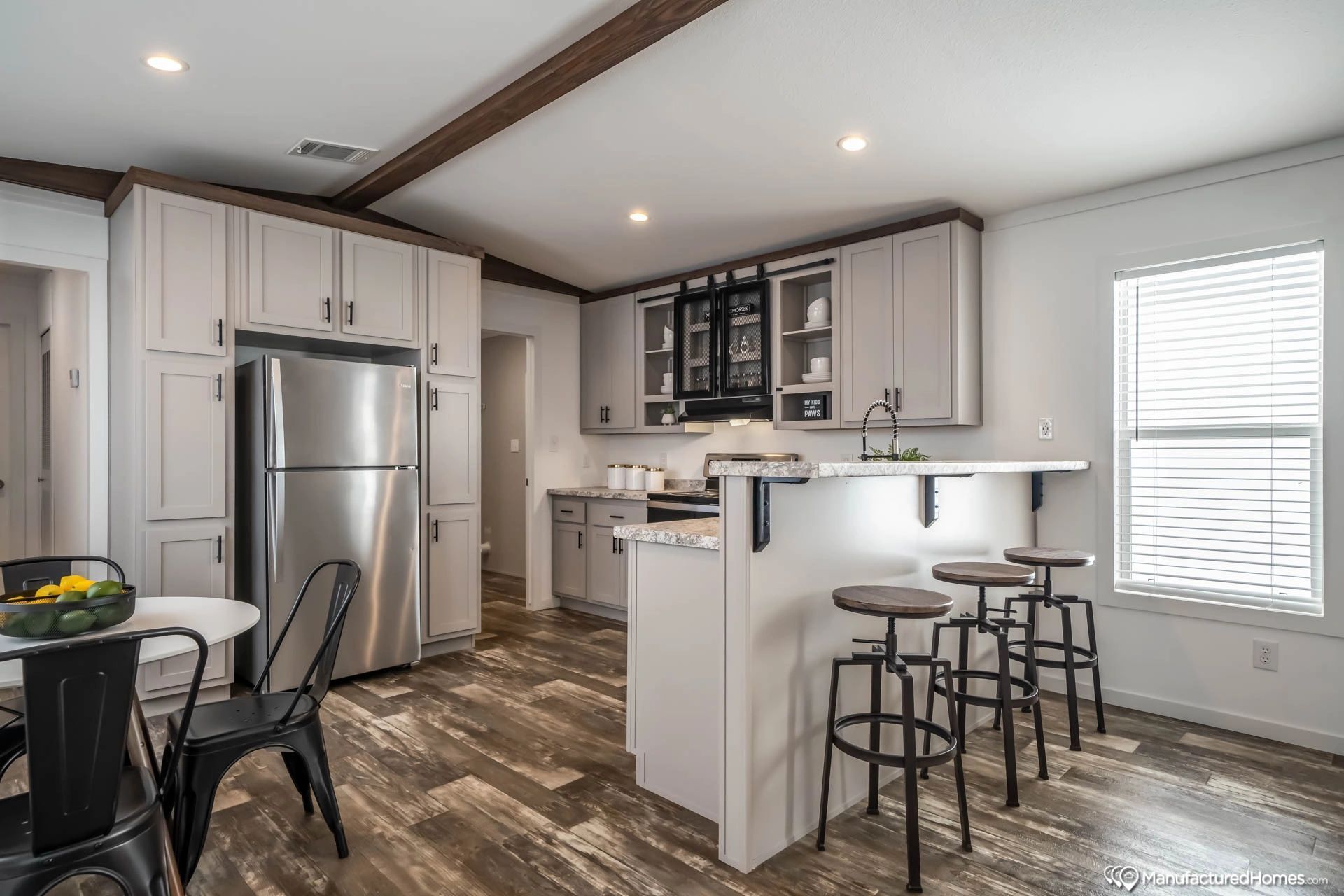 A kitchen with stainless steel appliances , white cabinets , a table and chairs.