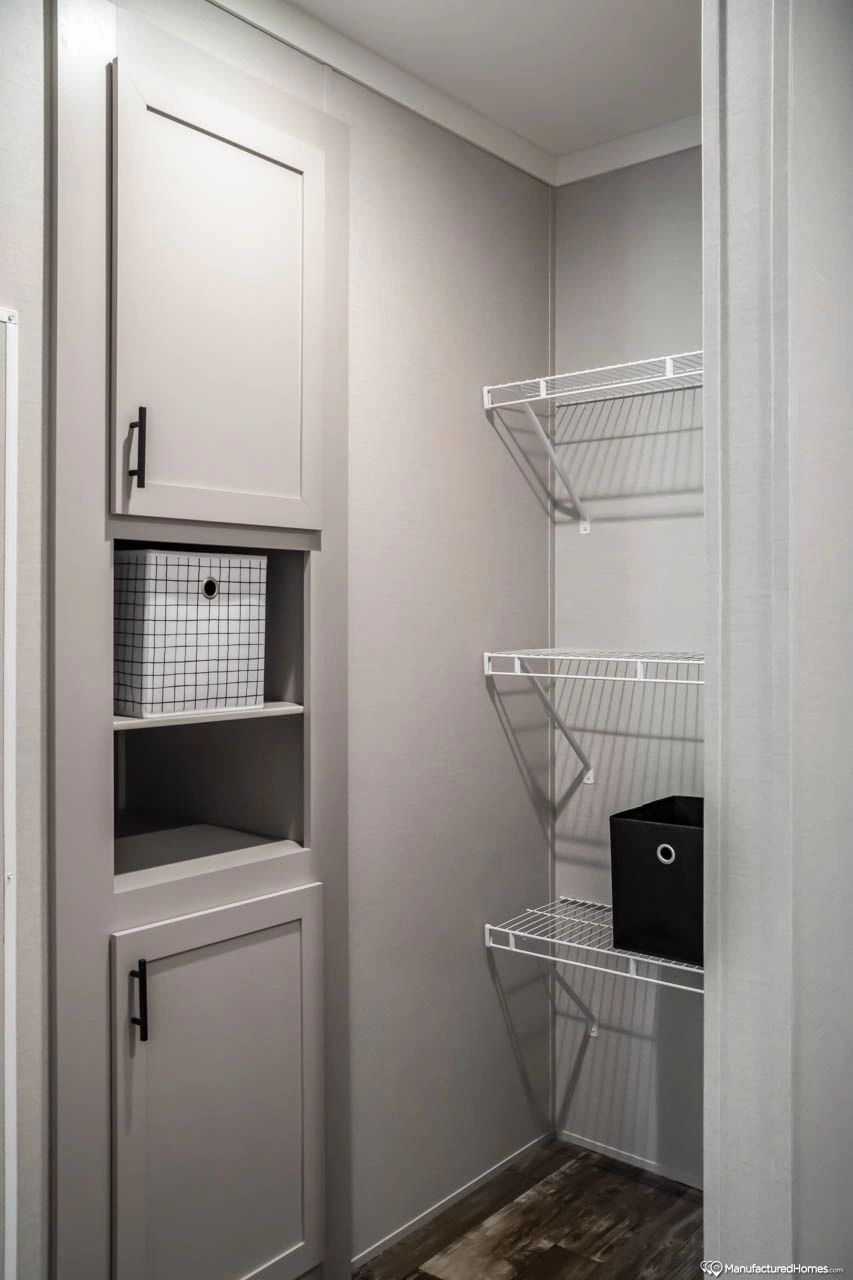 A walk in closet with shelves and cabinets in a house.