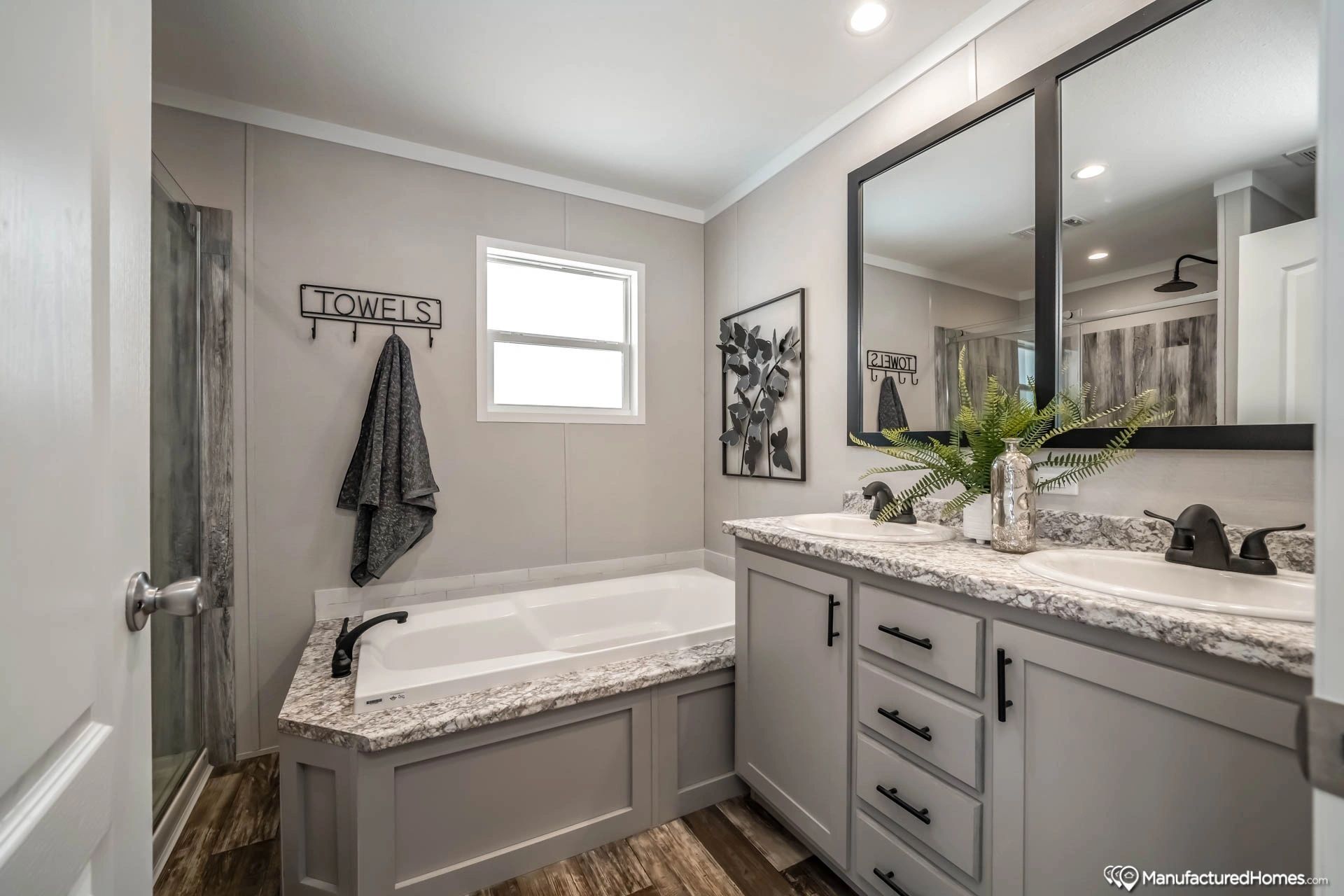 A bathroom with two sinks , a tub and a mirror.