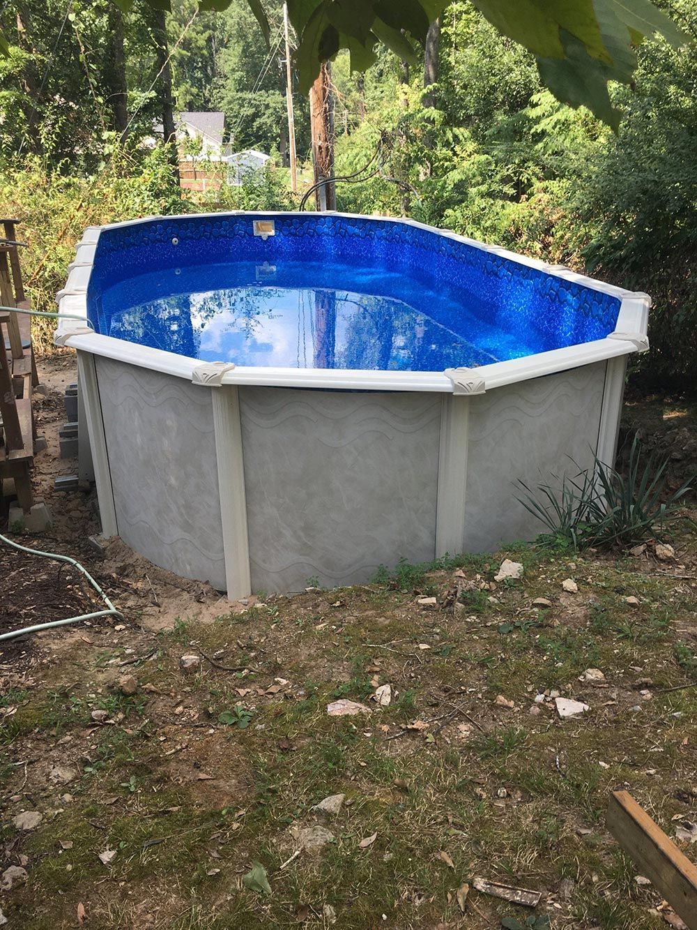 A large swimming pool is sitting on top of a lush green field.