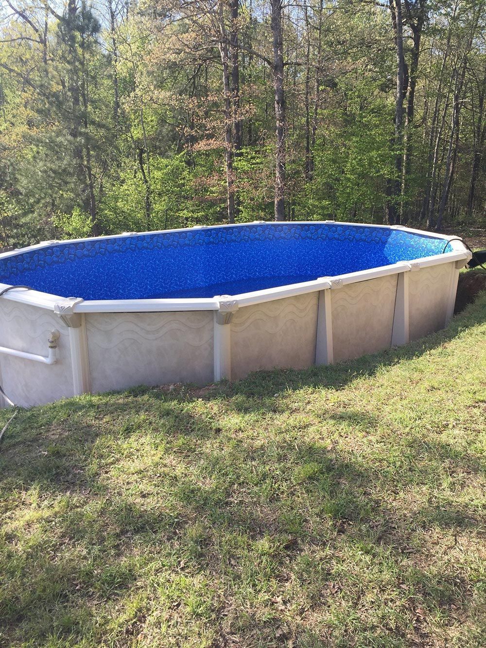 A large swimming pool is sitting on top of a lush green field.