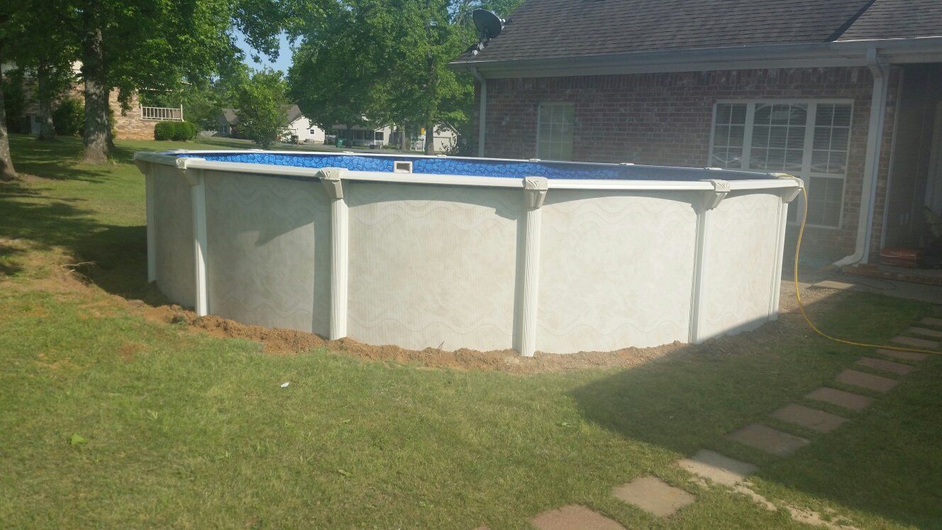 A large swimming pool is sitting in the backyard of a house.