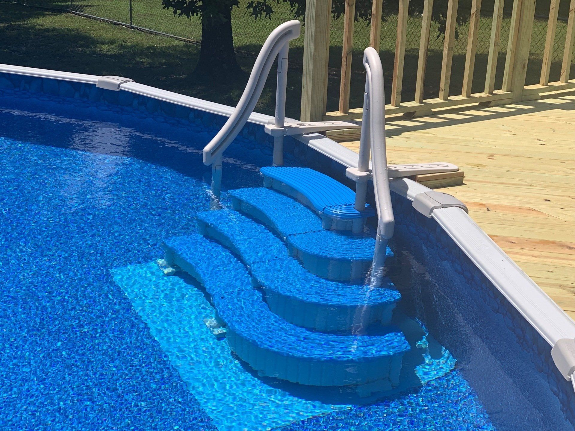 A swimming pool with blue steps and a wooden deck