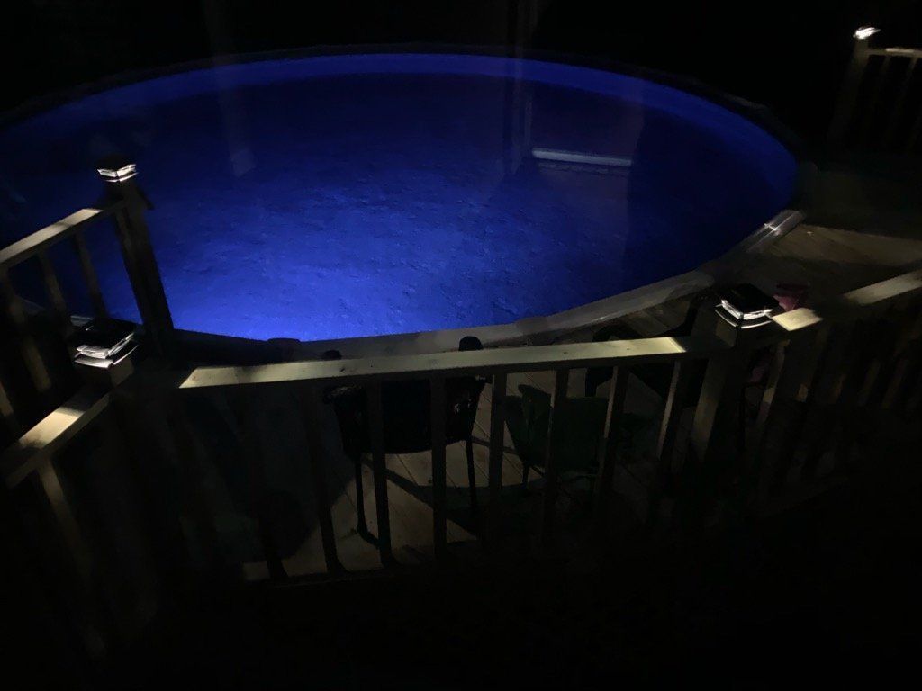 A swimming pool is lit up at night with blue lights