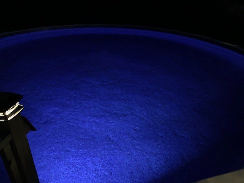 A swimming pool is lit up with blue lights at night