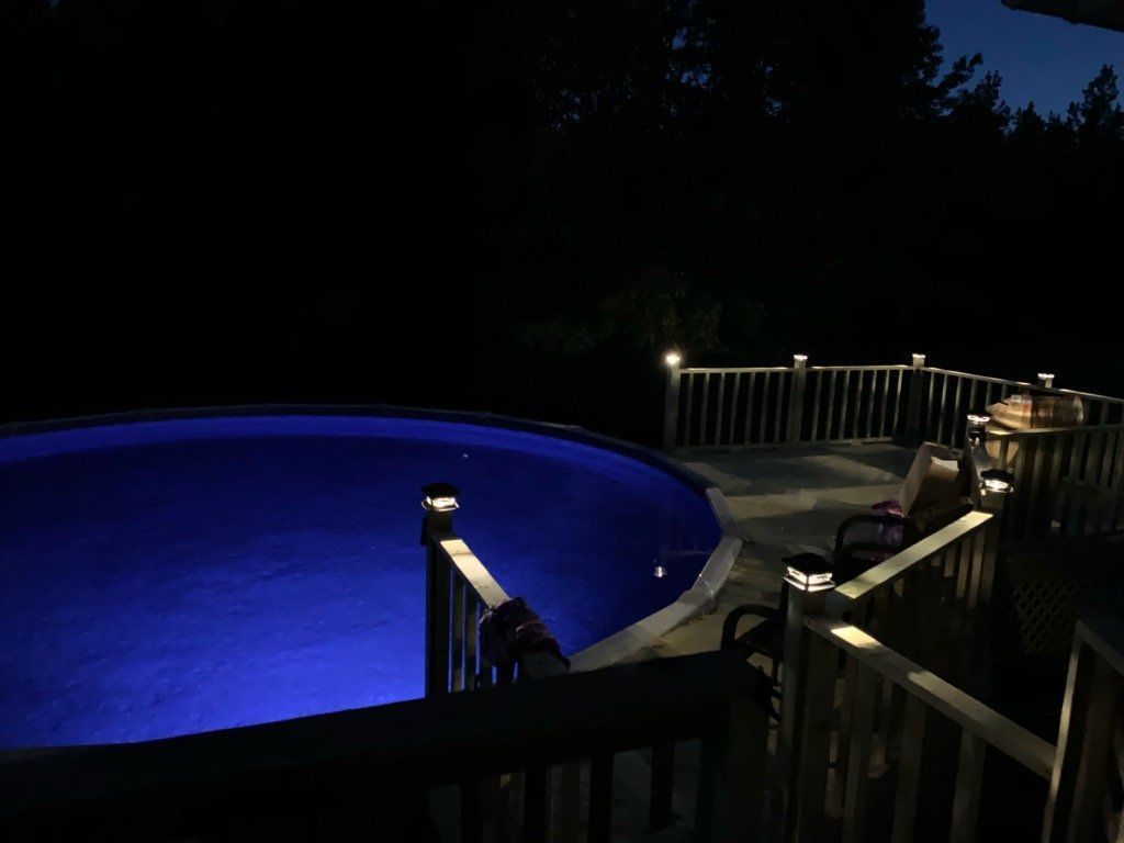 A swimming pool is lit up at night with blue lights.