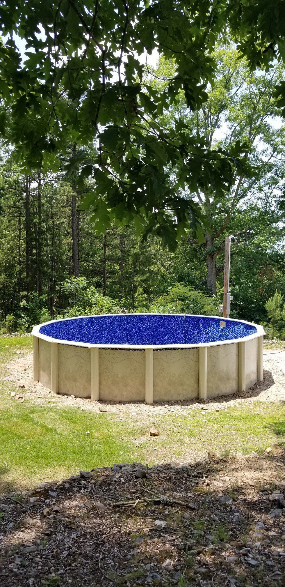A large swimming pool is sitting in the middle of a lush green field.