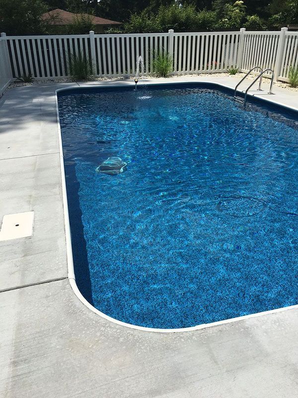 A large swimming pool with a white fence surrounding it.