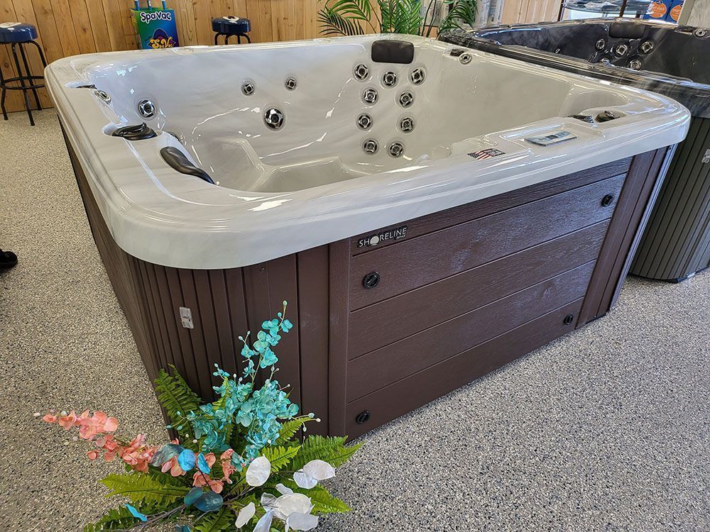 A hot tub is sitting in a room next to a vase of flowers.
