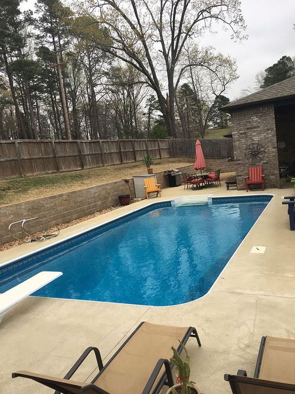 A large swimming pool is surrounded by chairs and a fence.
