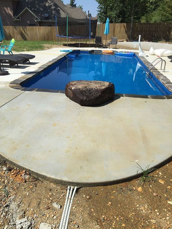 A large swimming pool with a large rock in the middle