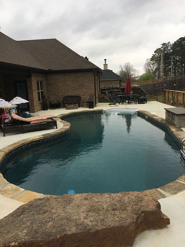 A large swimming pool is in the backyard of a house.