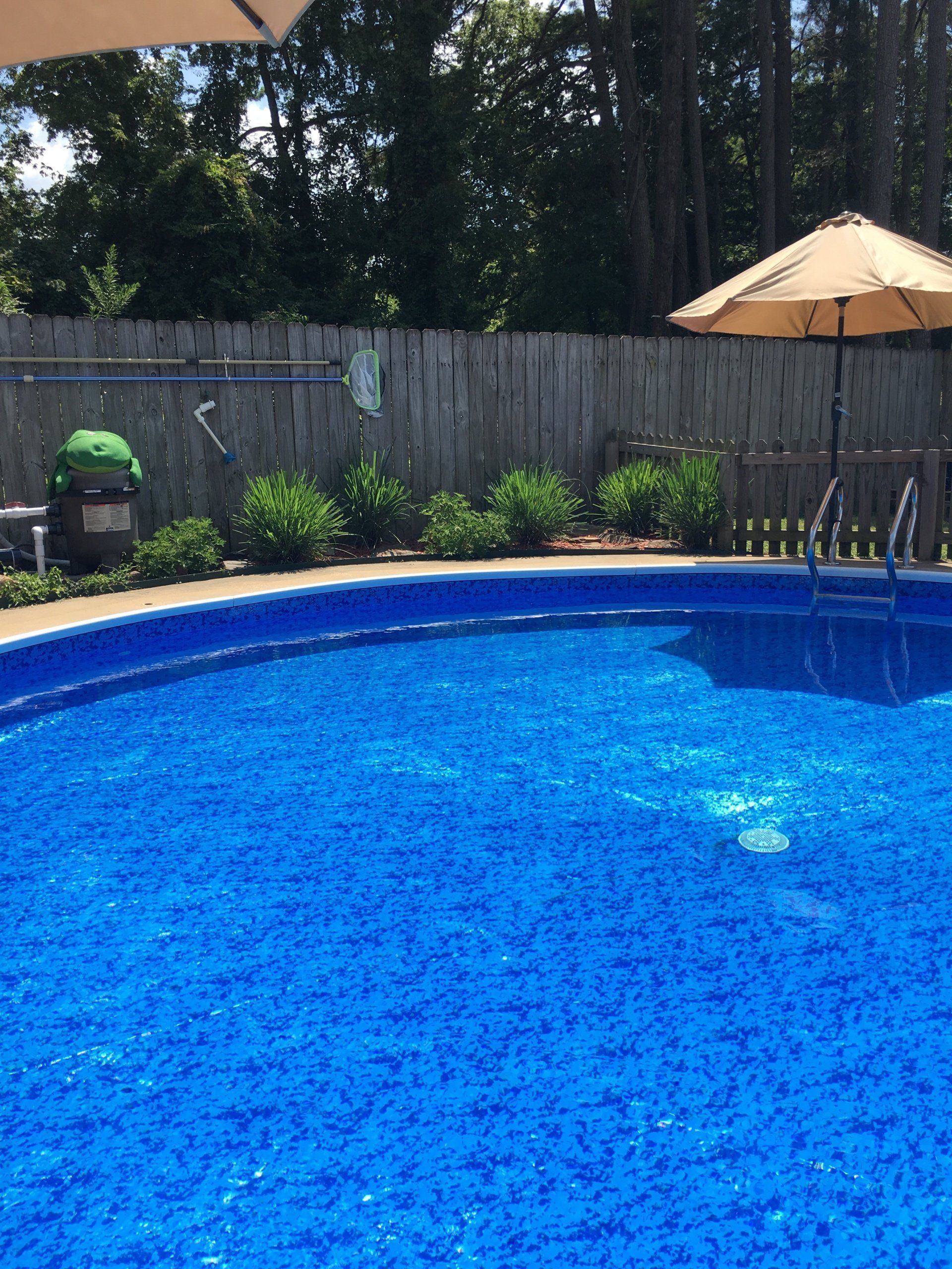 A large swimming pool with a wooden fence and umbrellas