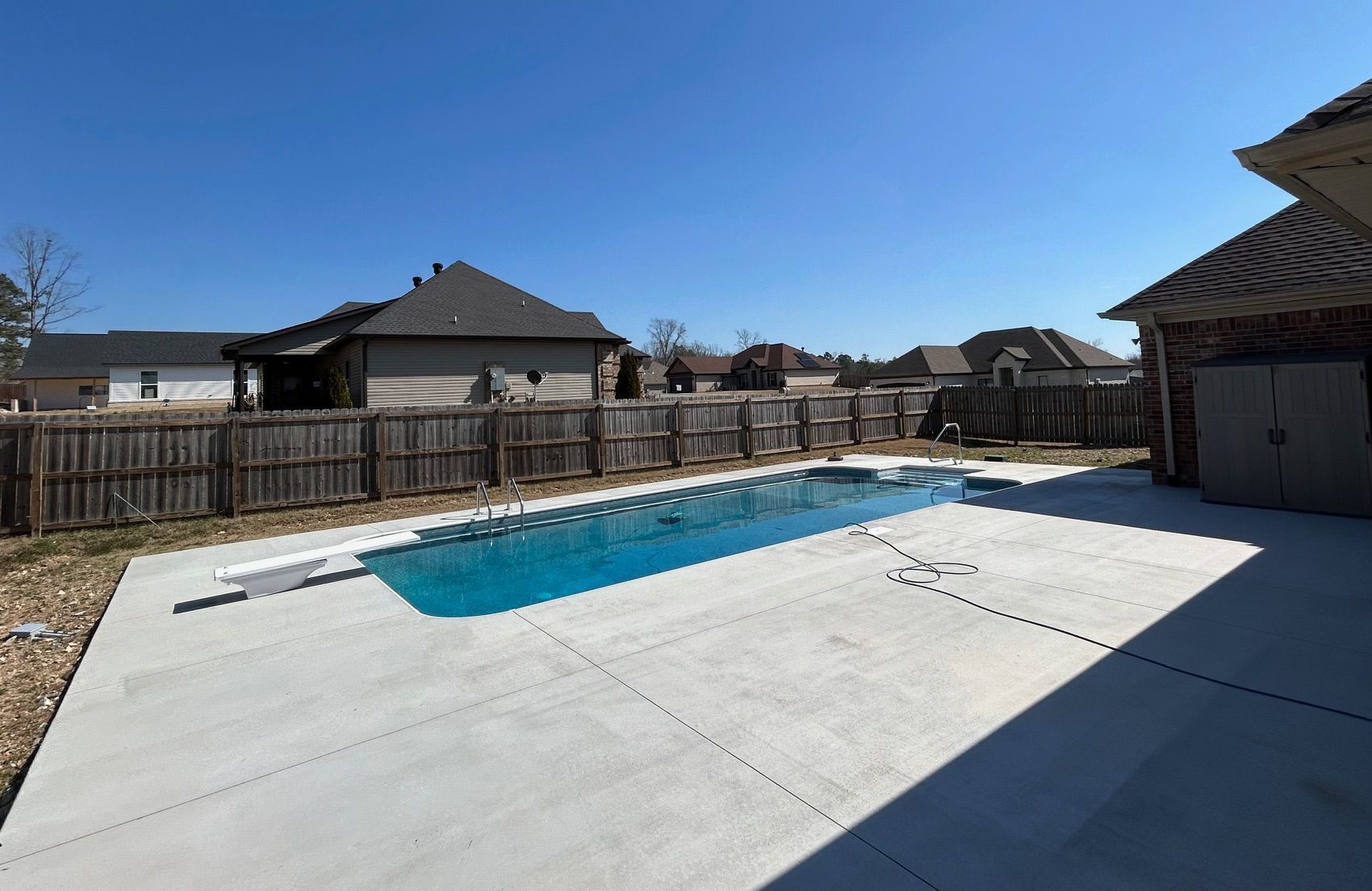 There is a large swimming pool in the backyard of a house.