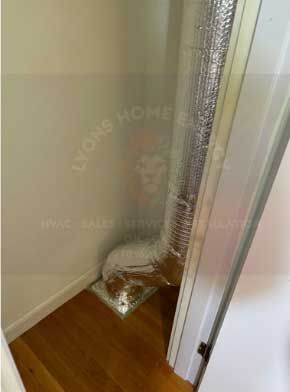 Flexible ductwork installed in a corner closet. Silver insulation contrasts with white walls and a wooden floor.