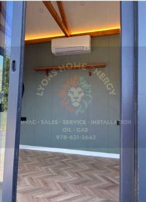 Interior view of a room with a green wall, air conditioner, and Lyons Home Energy logo.