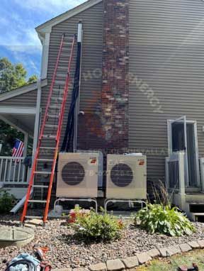 Exterior view of a house with air conditioning units next to a brick chimney and a ladder.