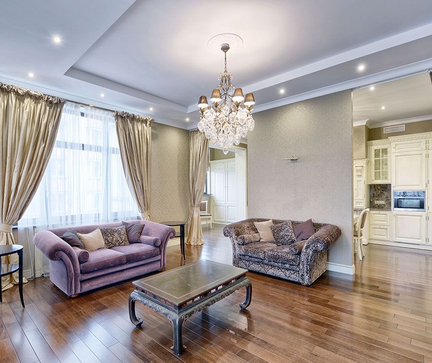 A living room with two couches , a coffee table and a chandelier.