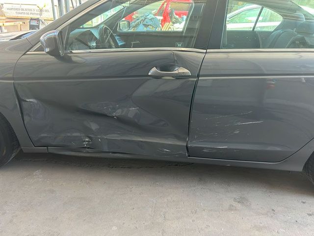 Damaged gray car door with dents and scratches in a parking garage