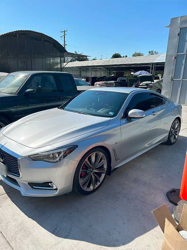 Silver coupe parked outdoors in a lot under a clear blue sky