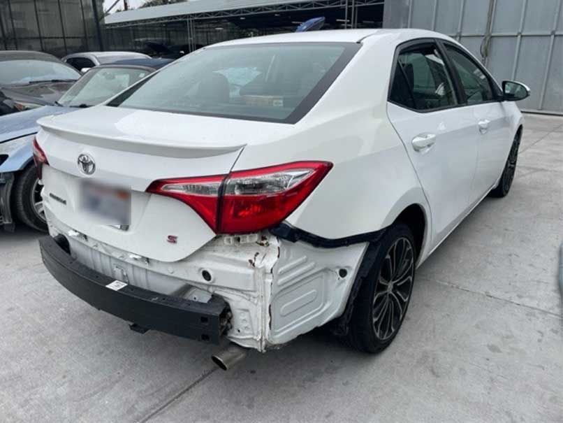 White sedan with rear-right side damage and missing bumper in a parking lot