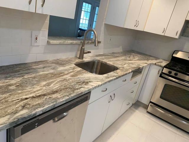 Modern kitchen with granite countertops, double sink, white cabinets, and stainless steel stove and dishwasher