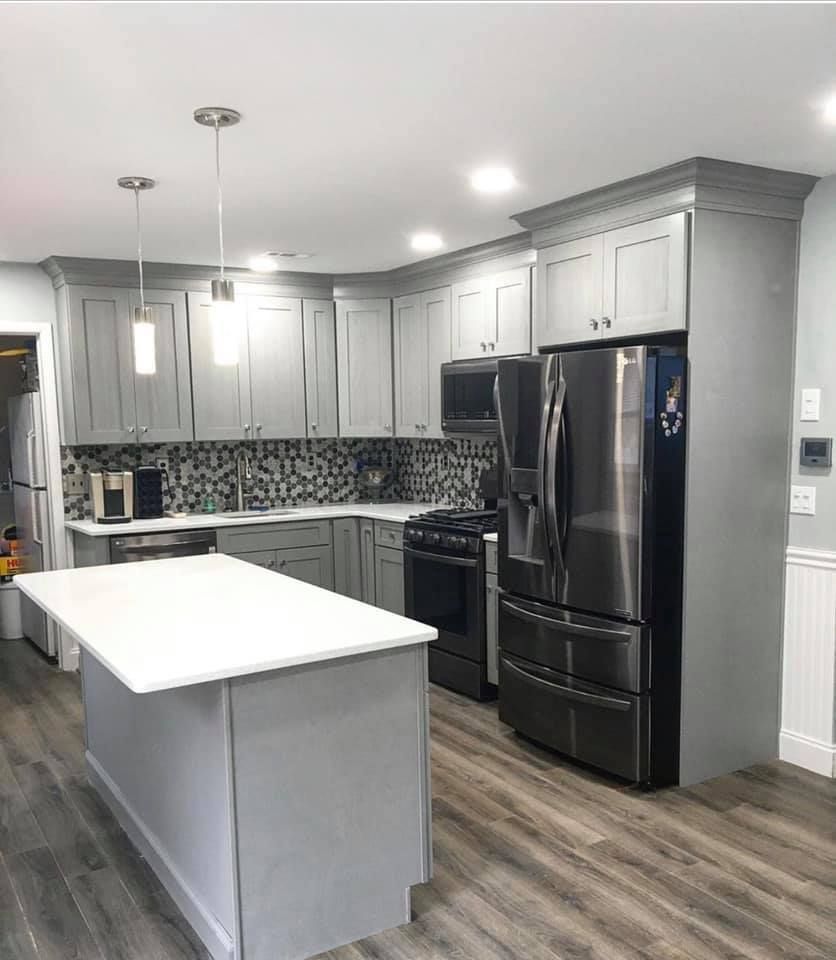 Modern kitchen with gray cabinets, white island, stainless appliances, and wood-look flooring