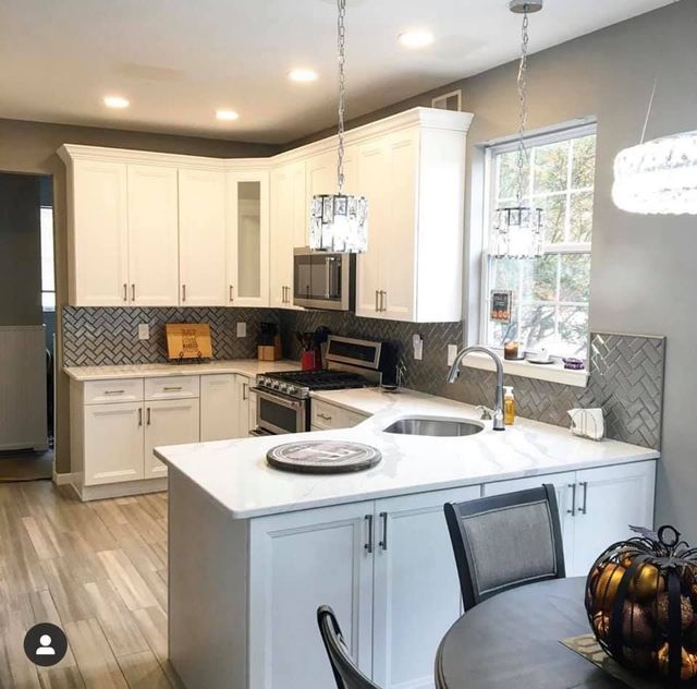Bright modern kitchen with white cabinets, gray walls, island, stainless appliances, and pendant lights