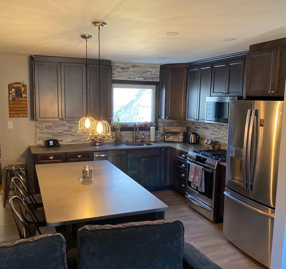 Modern kitchen with dark cabinets, stainless steel appliances, and a center island lit by pendant lights