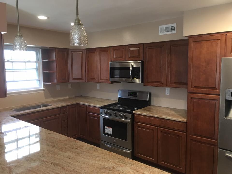 Modern kitchen with brown cabinets, stainless steel appliances, and a light countertop near a window.