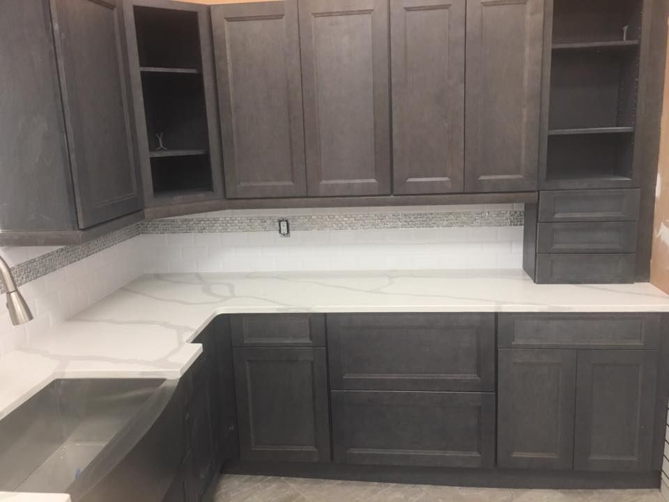 Dark wood kitchen cabinets and white countertops in an unfinished kitchen.