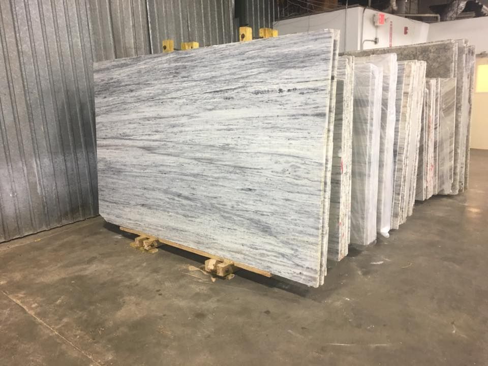 Stacked slabs of white and gray stone in a warehouse, wrapped on wooden pallets