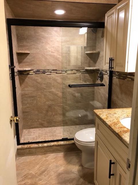 Bathroom with glass-enclosed shower, beige tile, white toilet, and granite vanity.
