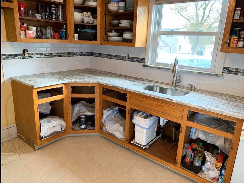 Partially installed kitchen cabinets under a window, with an L-shaped countertop and exposed storage below