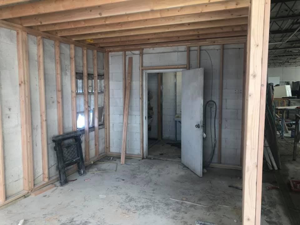 Unfinished room with exposed studs, concrete floor, and an open white door