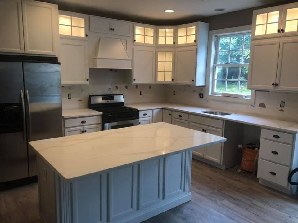 Bright modern kitchen with white cabinets, stainless fridge, black stove, and a large white island.