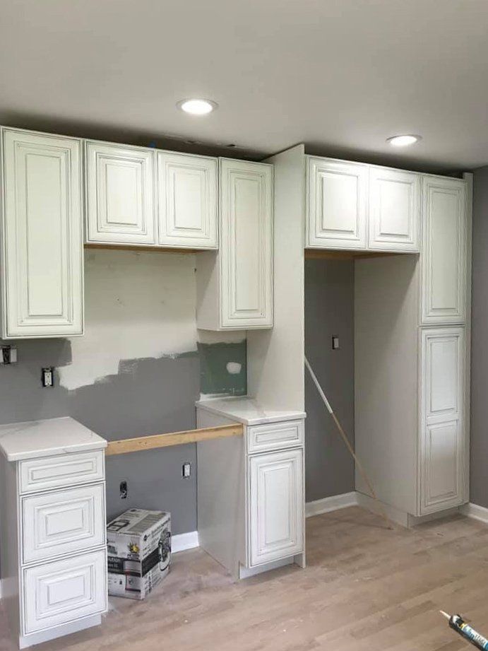 Unfinished kitchen with white cabinets, gray walls, and a countertop under recessed lights
