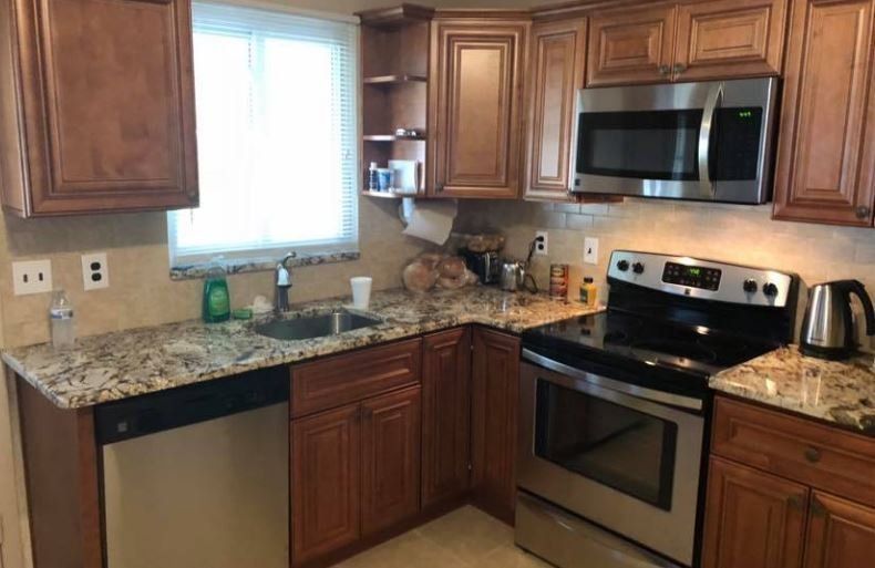 Modern kitchen with wood cabinets, granite counters, stainless steel appliances, and a window over the sink