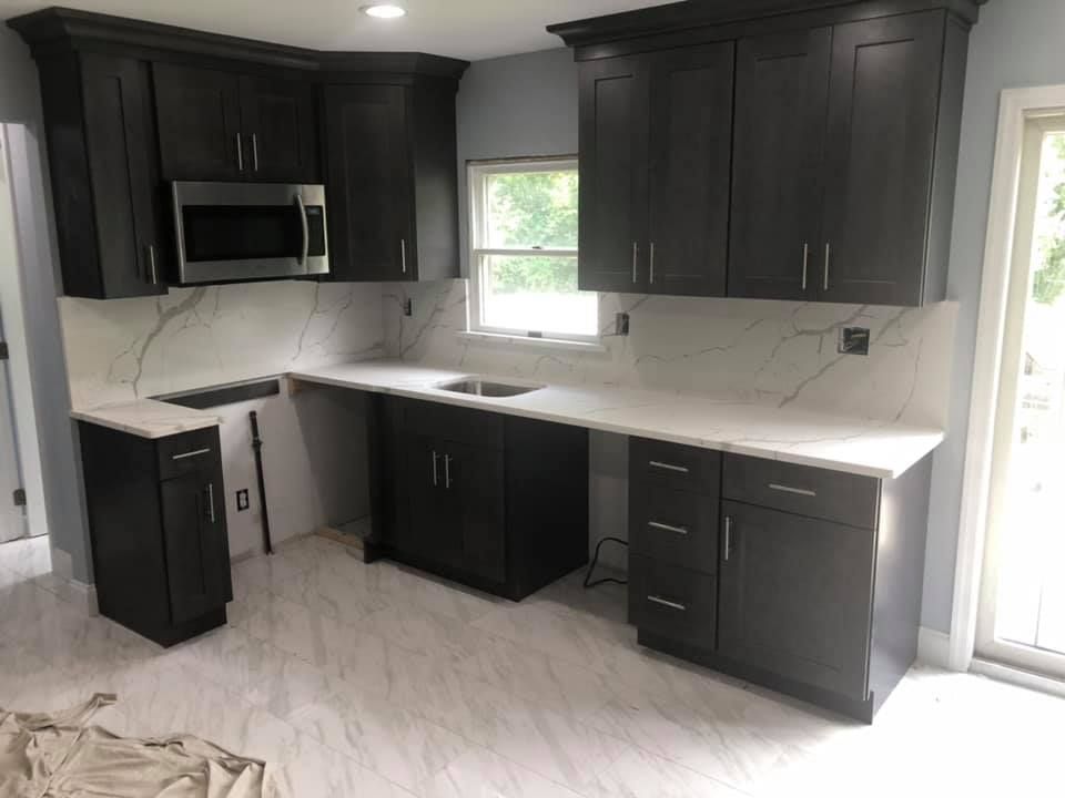 Modern kitchen with dark cabinets, white countertops, and stainless steel appliances