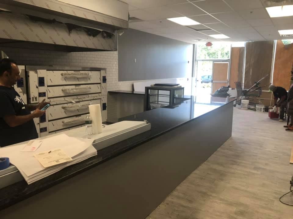 Indoor counter with a person serving papers beside a large printer in a lobby or office area
