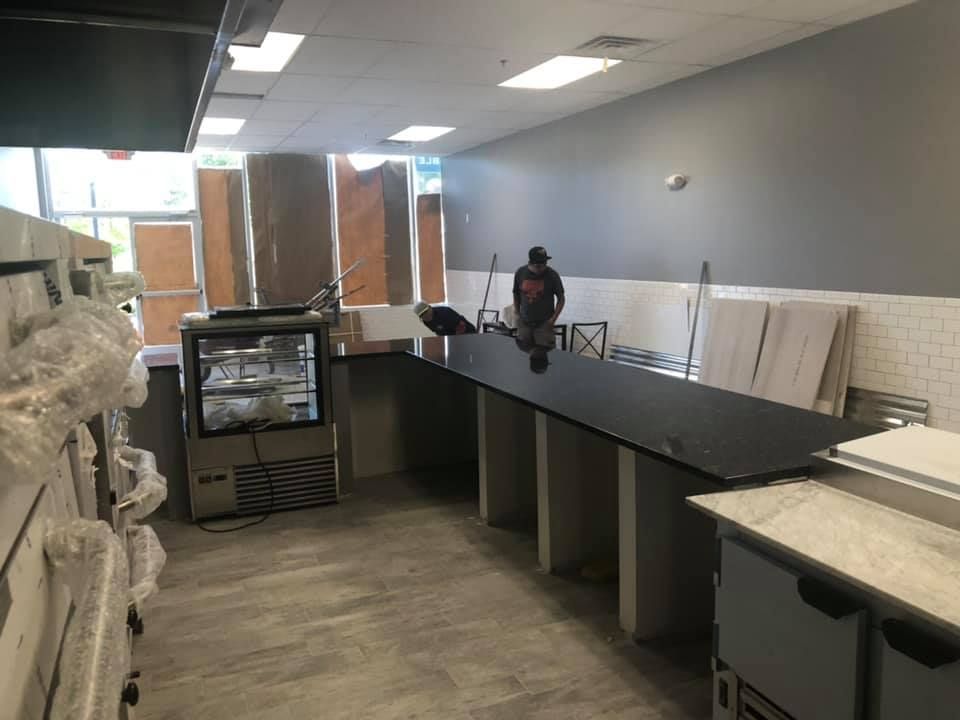 Empty retail counter area with black display cases, gray walls, and stacked boards in the back.