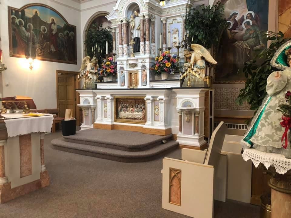 Church altar with white and gold decorations, flowers, and religious artwork in a quiet sanctuary
