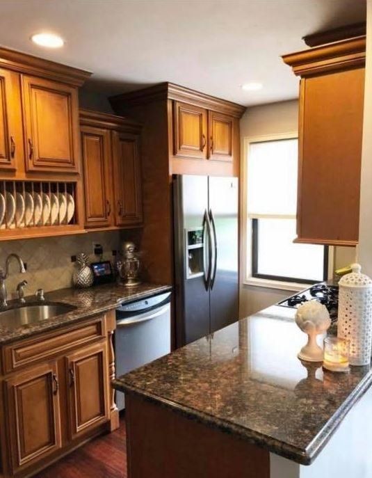 Modern kitchen with dark wood cabinets, stainless steel appliances, and granite countertops with a central island